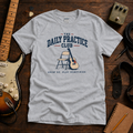 Daily Practice Club tee by Steady Strum, laid flat on a wood desk with guitar gear