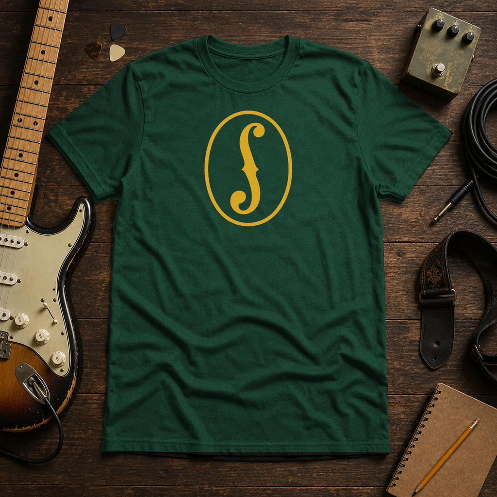 Forest Green F-Hole tee by Steady Strum, laid flat on a wood desk with guitar gear