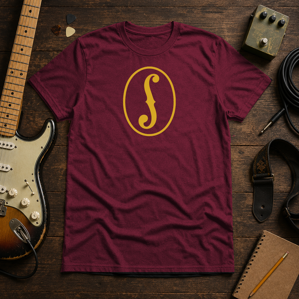 Maroon F-Hole tee by Steady Strum, laid flat on a wood desk with guitar gear