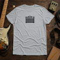 Sport Grey Pixel Amp tee by Steady Strum, laid flat on a wood desk with guitar gear