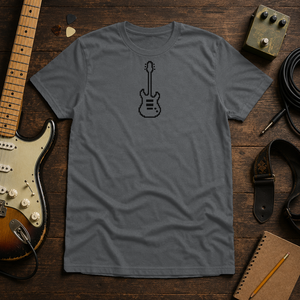 Graphite Heather Pixel Guitar tee by Steady Strum, laid flat on a wood desk with guitar gear