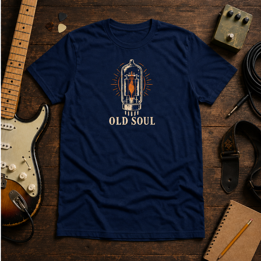 Navy Old Soul tee by Steady Strum, laid flat on a wood desk with guitar gear