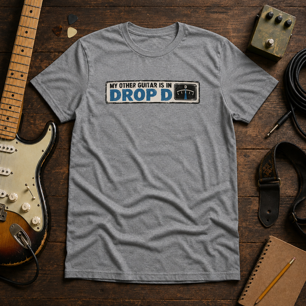 Grey Other Guitar Is In Drop D tee by Steady Strum, laid flat on a wood desk with guitar gear