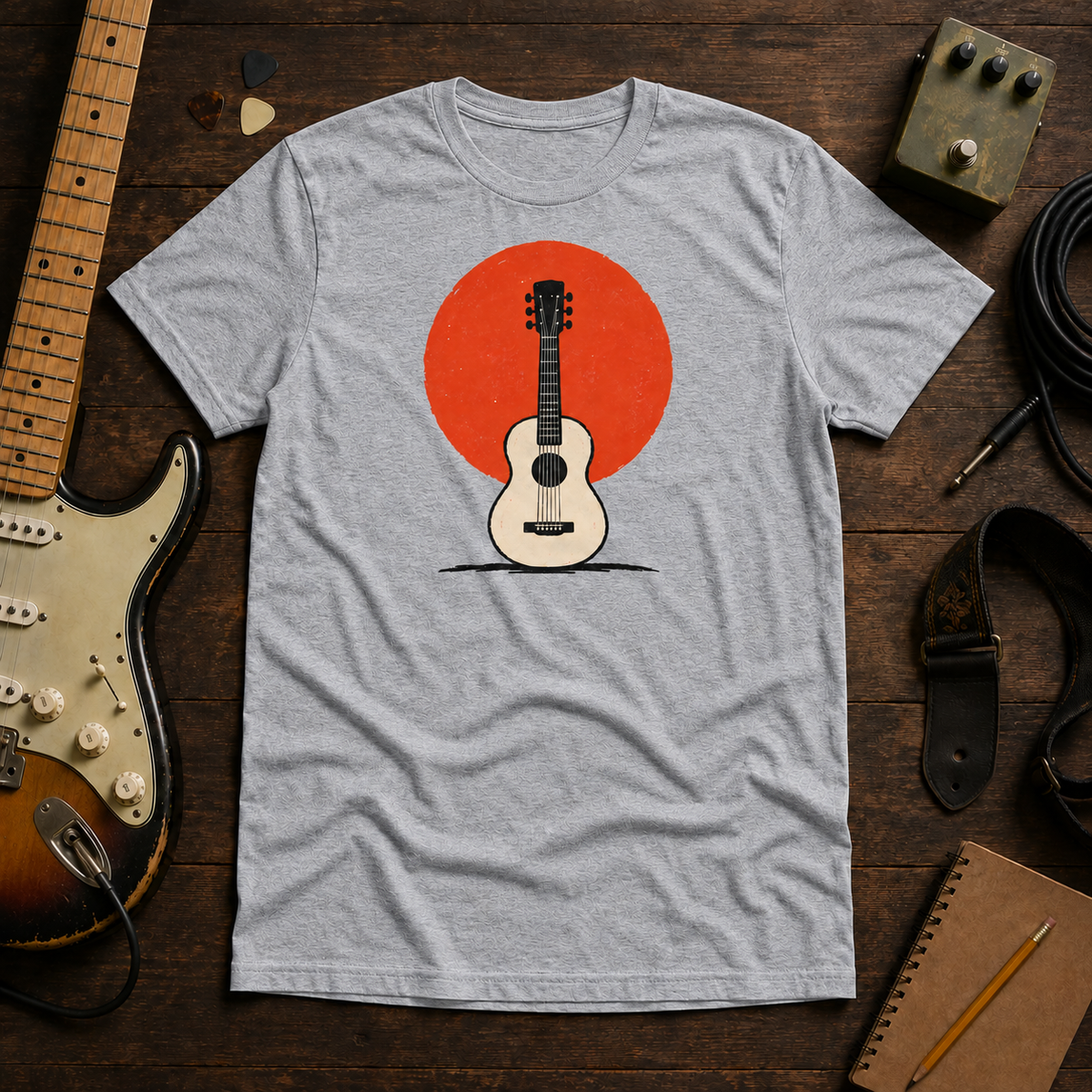 Grey Sun. Set. tee by Steady Strum, laid flat on a wood desk with guitar gear
