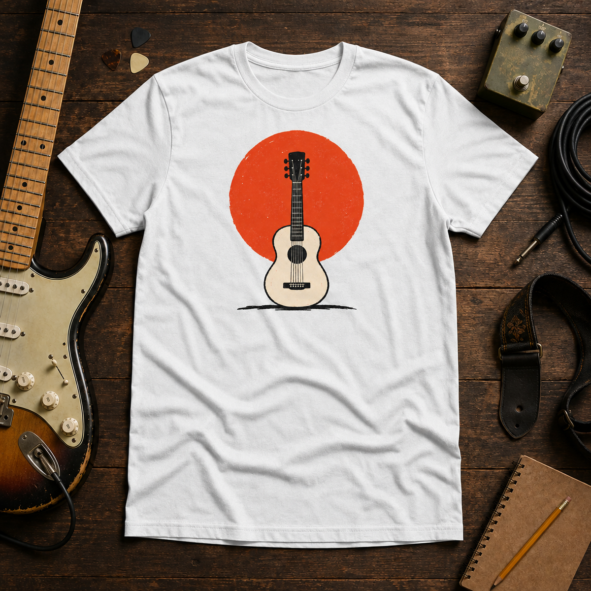 White Sun. Set. tee by Steady Strum, laid flat on a wood desk with guitar gear